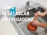 Manos usando un desatascador para desatascar fregadero.
