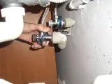Ręka trzyma zawór, pokazując, jak wykrecic urwany zawor od wody.
