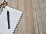 Notatnik z długopisem i okularami, gotowy do spisania opinii o uczniu.
