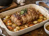 Un savoureux roti de porc au four, doré et juteux, mijotant avec des pommes de terre et des carottes dans un plat en céramique.