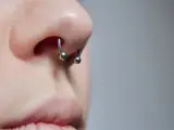 Zbliżenie na nos z kolczykiem typu septril piercing. Metalowy okrąg z dwoma kulkami subtelnie zdobi przegrodę nosową.