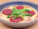 Mini pizza na patelni z serem, rukolą i plasterkami pikantnej salsiccii.