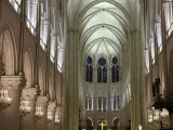 Interior de Notre Dame, con sus impresionantes arcos góticos, vitrales y candelabros dorados. Las **entradas Notre Dame** se abren a este majestuoso espacio.