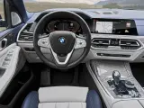 Wnętrze BMW X7: kierownica, ekran multimedialny z nawigacją i muzyką, panel klimatyzacji, dźwignia zmiany biegów.