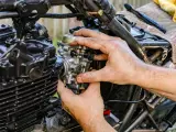 Ręce mechanika regulują gaźnik motocykla, pokazując, jak działa ssanie.