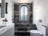 Bagno di lusso con vasca doccia in muratura, rivestimenti in marmo e vista panoramica.