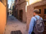 Młoda osoba z plecakiem idzie wąską uliczką w Marrakeszu. Czy w Marrakeszu jest bezpiecznie? Tak, zwiedzanie jest przyjemne.