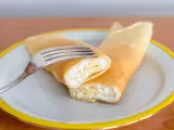 Naleśniki z serem, jeden przekrojony, widelcem na talerzu. Pyszny ser do naleśników czeka na spróbowanie.