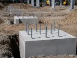 Solidne fundamenty z żelbetonu z wystającymi śrubami czekają na konstrukcję.