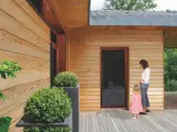 Piękna elewacja z drewna, której impregnacja zapewnia trwałość i naturalny wygląd. Kobieta z dzieckiem na tarasie.