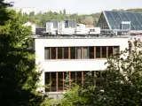 Nowe budynki od września 2026 będą musiały posiadać instalację fotowoltaiczną. Na dachu budynku widać panele i klimatyzatory.