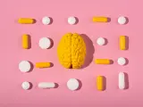 Żółty model mózgu otoczony białymi i żółtymi tabletkami i kapsułkami, symbolizującymi równowagę neuroprzekaźników, jak serotonina.
