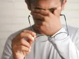 Zmęczony pracownik pociera oczy, trzymając okulary. Marzy o urlopie bezpłatnym zgodnie z kodeksem pracy.