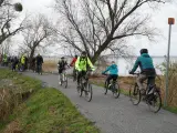 Grupa rowerzystów przemierza malownicze ścieżki rowerowe Szczecina, ciesząc się aktywnym wypoczynkiem nad wodą.