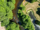 Dwie kajaki płyną rzeką pośród zieleni. To wspaniałe **Kociewie atrakcje** dla miłośników przyrody i aktywnego wypoczynku.