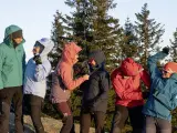 Sechs Personen in bunten Hardshelljacken stehen vor Bäumen. Eine Hardshelljacke schützt vor Wind und Wetter.