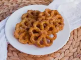 Buñuelos dorados con azúcar y canela en un plato blanco.