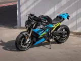 Potężny motocykl BMW S1000R w jaskrawych kolorach niebieskim i żółtym, gotowy do jazdy po torze.