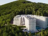 Nowy hotel w Wiśle, Crystal Mountain, wtopiony w zielone zbocze góry. Nowoczesna architektura z licznymi balkonami i basenem.