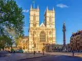 L'abbaye de Westminster, majestueuse et illuminée par le soleil, se dresse fièrement avec ses tours jumelles. Une colonne commémorative se dresse à droite.