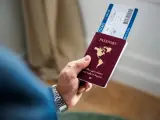 Dłoń trzyma paszport i bilet lotniczy.