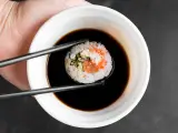 Pałeczkami zanurzam sushi w sosie kabayaki.