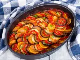 Gotowy ratatouille przepis w naczyniu żaroodpornym, z plasterkami cukinii, bakłażana i pomidorów, polany sosem.