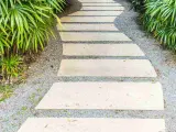 Un sentiero sinuoso con lastre di pietra e ghiaia, circondato da vegetazione lussureggiante. Idee marciapiede casa per un ingresso accogliente.