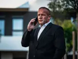 Krzysztof Bukowski, reżyser, w garniturze rozmawia przez telefon.