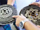 Mechanik pokazuje dwa dyski sprzęgła: jeden nowy, drugi mocno zużyty, z widocznymi śladami spalonego sprzęgła.