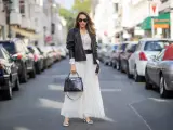 Elegancka kobieta w białej, plisowanej spódnicy i czarnej ramonesce. Idealne buty do plisowanej spódnicy to te, które widzisz: białe czółenka z czarną kokardką.