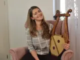 Uśmiechnięta kobieta trzyma instrument muzyczny, który wygląda jak skorupa żółwia.
