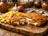 Cachopo jugoso, crujiente por fuera y relleno de jamón y queso fundido. Una deliciosa receta de cachopo, acompañada de patatas fritas.
