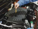 Mechanik sprawdza poziom oleju w silniku Peugeot 508. Wymiana oleju w skrzyni manualnej to ważny element dbania o auto.