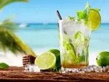 Orzeźwiający mojito przepis na plaży. Szkło z lodem, limonką i miętą, z palmą i morzem w tle.