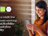 A woman smiles while looking at her phone, with icons representing financial flexibility and a working capital line of credit.