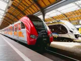 Dwa nowoczesne pociągi, czerwony i srebrny, czekają na pasażerów na dworcu. To idealny pociąg do poznania nowych miejsc.