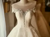 Magnifique robe de mariée, la couleur est un blanc éclatant, ornée de perles et de dentelle fine.