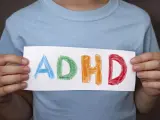 Mani di bambino tengono un foglio con la scritta "ADHD" colorata. Riconoscere i sintomi dell'ADHD è il primo passo.
