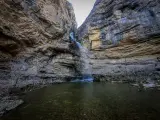 La cascada del Gollorio cae entre imponentes paredes rocosas, formando un estanque sereno.