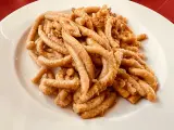 Pici all'aglione, uno dei piatti tipici di Arezzo, serviti su un piatto bianco.