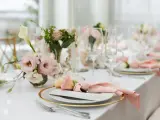 Ett vackert dukat bord med rosa dekorationer, blommor och glas. En elegant dukning för ett speciellt tillfälle.