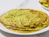 Piatto di crepes di zucchine verdi, sottili e leggermente dorate, impilate su un piatto bianco.