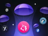 Co to jest airdrop kryptowaluty? Ilustracja pokazuje kilka tokenów kryptowalutowych spadających na spadochronach, symbolizując darmowe rozdawanie cyfrowych aktywów.