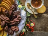 Cesto pieno di biscotti fatti in casa al cioccolato e alla vaniglia, accanto a una tazzina di caffè e bacche rosse.