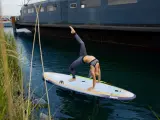 Frau macht Yoga-Brücke auf SUP-Board. Stand up paddle gesund und fördert Balance.