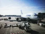 Lufthansa A380 na płycie lotniska we Frankfurcie. W tle widać inne samoloty i budynki terminali, typowe dla lotnisk w Niemczech.