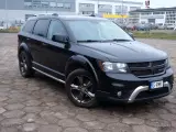 Czarny Dodge Journey 3.6 zaparkowany na placu z kostki brukowej. W tle budynki i inne samochody.