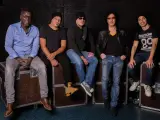 Les membres de Trust (groupe) posent ensemble, assis sur des flight cases, prêts pour leur prochaine performance.