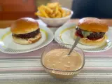 Två hamburgare med pommes frites och en skål med hemlagad hamburgerdressing. Perfekt för en mysig hemmakväll!